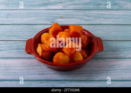 Spanish gastronomy concept. Clay plate with fried potatoes with spicy sauce called in Spain "Patatas Bravas" Stock Photo