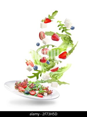 Plate with tasty salad and flying ingredients on white background Stock Photo