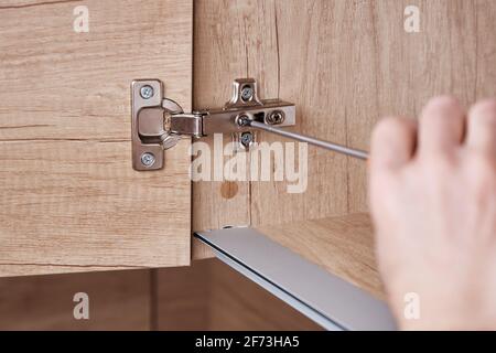 Srewdriver fixing kitchen cabinet door, close up Stock Photo