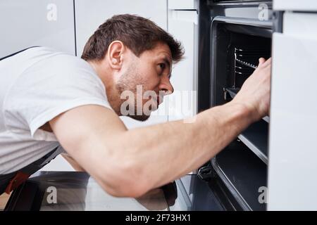 Appliance maintenance. Man fixing problem in the oven in kitchen Stock Photo