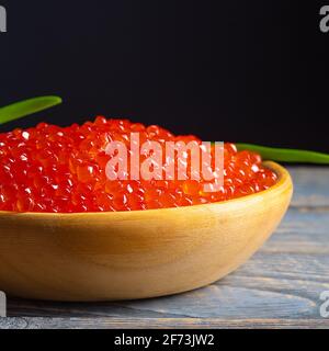 Red caviar in a wooden cup on a wooden background. Place for advertisement, logo, label, mockup, mock-up. Stock Photo