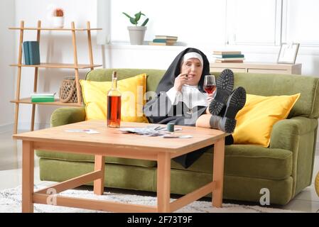 Senior nun with cigar and alcohol at home Stock Photo