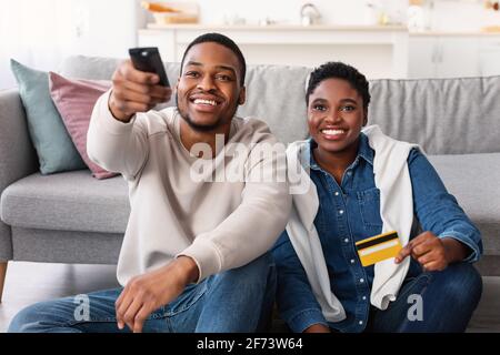 Black couple holding remote control and credit card Stock Photo