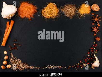 Different types of Indian spice colorfuls and spices on a dark stone background. Dark slate stone tablet for inscriptions with heaps of oriental and A Stock Photo