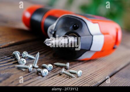 Home repair of kitchen furniture. Twisting a loose self-tapping screw with an electric screwdriver Stock Photo