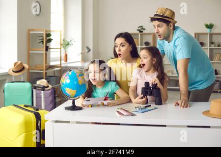 Funny amazed family with children finding location for travel on earth globe Stock Photo