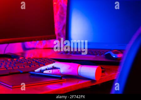 Digital design concept with a robot. Creative designer workplace in neon light. Digital tablet for drawing and an artificial arm with a pen. Distant w Stock Photo