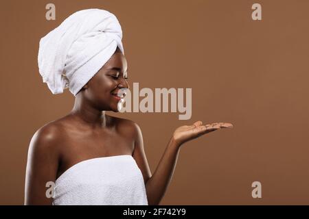 Body Care. Smiling Black Woman Holding Something On Empty Palm After Bath Stock Photo