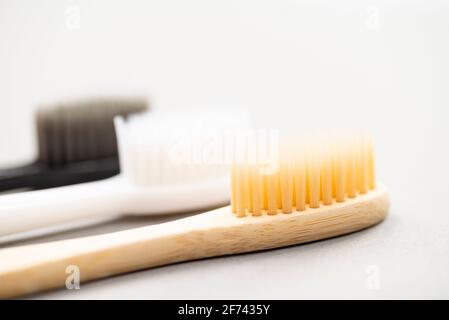 Natural eco-friendly bamboo toothbrush and two plastic toothbrushes on a white background close-up. Choose a plastic or wooden toothbrush. Recycling Stock Photo