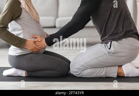 Couples Pregnancy Yoga. Cropped Shot Of Muslim Spouses Training Together At Home Stock Photo