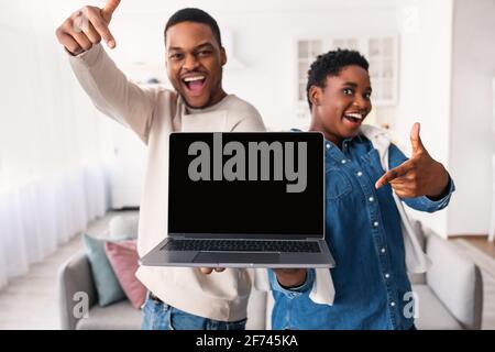 Black couple showing blank empty laptop screen for mock up Stock Photo