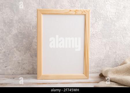 White wooden frame mockup with linen textile on gray concrete background. Blank, vertical orientation, still life, copy space. Stock Photo