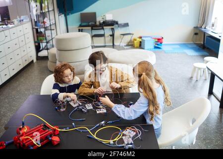 High angle view at group of children building robots and experimenting with electric circuits in engineering class at school, copy space Stock Photo