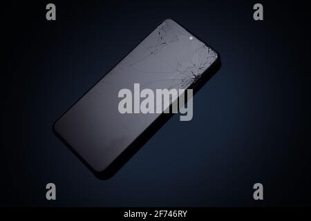 Modern touchscreen smartphone with broken screen on dark background Stock Photo