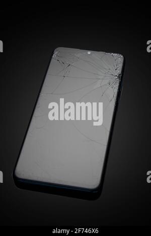 Modern touchscreen smartphone with broken screen on dark background Stock Photo