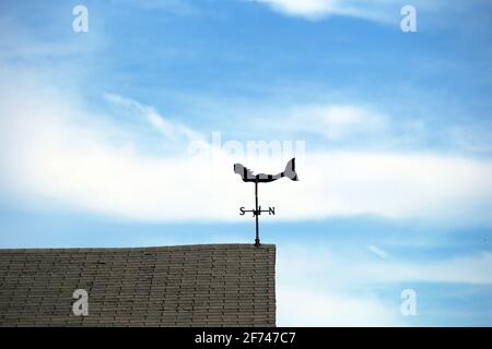Ocean sea nautical mermaid weathervane on a sunny seacoast home rooftop pointing wind from the south, light cirrus clouds and blue sky background Stock Photo