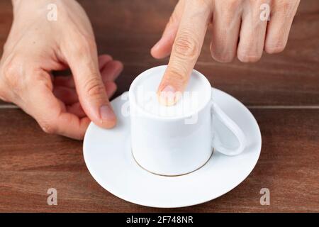 A caucasian woman is performing fortune reading ( kahve fali ) using leftover coffee grounds in ceramic Turkish coffee cup. A popular activity in Turk Stock Photo