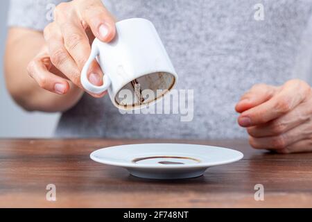A caucasian woman is performing fortune reading ( kahve fali ) using leftover coffe grounds in ceramic Turkish coffe cup. A popular activity in Turkey Stock Photo