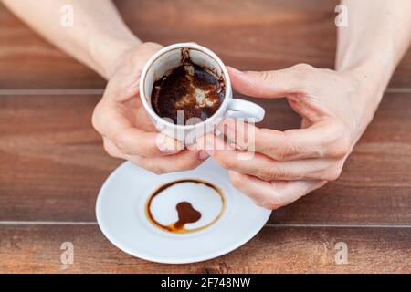 A caucasian woman is performing fortune reading ( kahve fali ) using leftover coffe grounds in ceramic Turkish coffe cup. A popular activity in Turkey Stock Photo