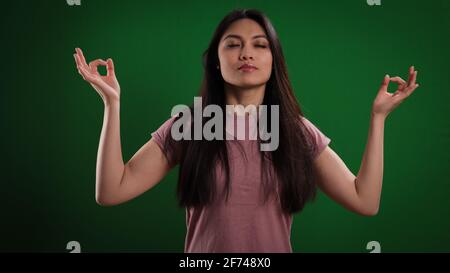 Young woman meditates in fromnt of a neutral background Stock Photo