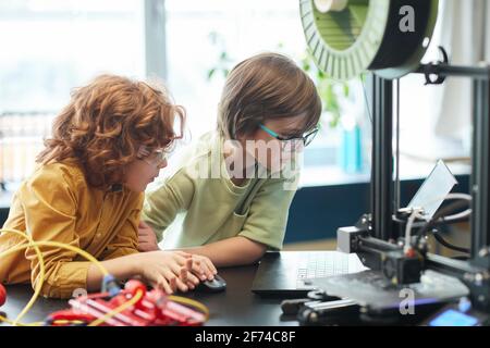 Portrait of two boys using 3D printer during engineering and robotics class at school, copy space Stock Photo
