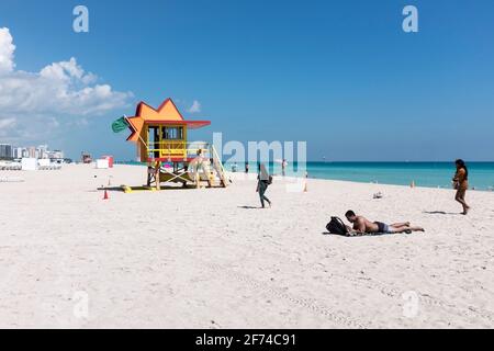 A man soaks up the sun under as perfect weather and crystal clear water greet the tourists on a quiet day at the beach, on South Beach, Miami Beach, Florida Stock Photo