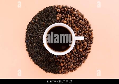 Beige flat lay background with white ceramic coffee cup, roasted coffee beans and dried tea leaves. Idea and composition, choice between coffee beans Stock Photo