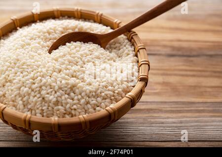 Glutinous rice in a bamboo colander set against a background of trees with copy space Stock Photo