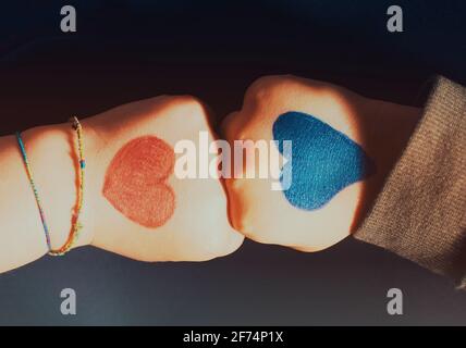 Two kid's hands, girl and boy in a fists gesture. Black background. Stock Photo