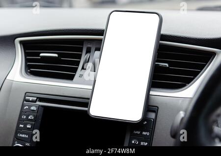 Mobile phone on the car air vent.Blank with white screen.Mock up smart phone in car. Stock Photo
