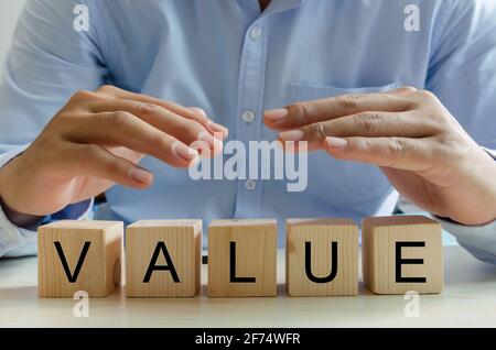 Hand businessman wooden cube value text. Business concept. Stock Photo