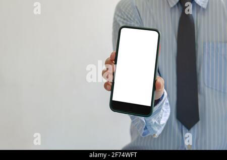 man holds a smartphone in hand. Mobile phone mockup white screen blank Standing Against. use for marketing advertising or promoting online product.Cli Stock Photo