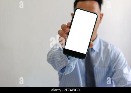 man holds a smartphone in hand. Mobile phone mockup white screen blank Standing Against. use for marketing advertising or promoting online product.Cli Stock Photo