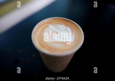 Shallow depth of field (selective focus) image with details of a decorated coffee in a paper cup. Stock Photo
