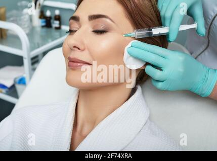 Woman with closed eyes receives beauty injections, macro. Mesotherapy procedure, skin refreshing. Stock Photo