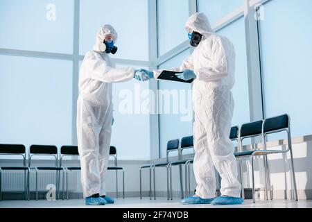 lab technicians in protective suits shaking hands. Stock Photo