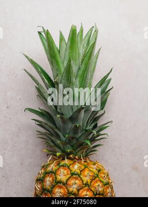 From above of ripe whole sweet pineapple placed on stone table in kitchen Stock Photo