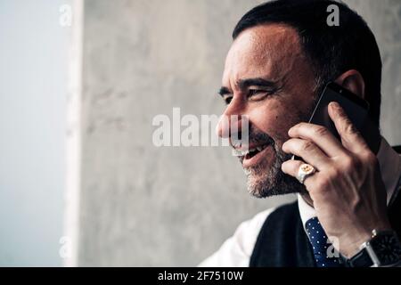 Crop happy middle aged Hispanic male entrepreneur speaking on cellphone while looking away in daytime Stock Photo