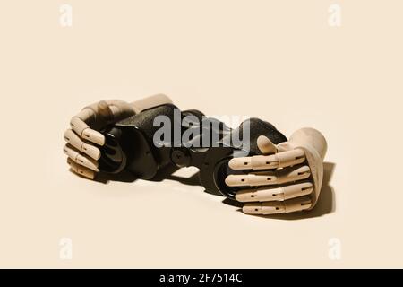 Decorative flexible wooden hands placed with retro binoculars on beige background in light studio Stock Photo