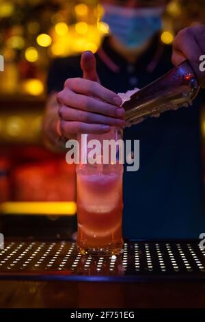 Hands of unrecognizable bartender putting crushed ice into the cup while preparing a cocktail in the bar Stock Photo