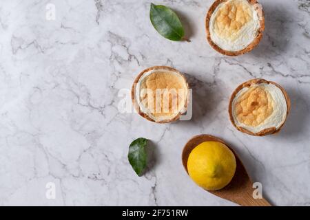 Top view of yummy homemade meringue tarts placed on table with fresh lemon and green leaves Stock Photo