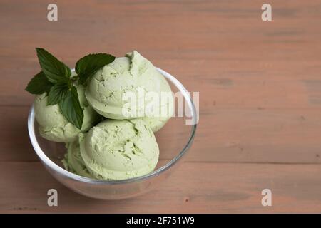 Glass cup with matcha green tea ice cream balls on wooden background . Stock Photo