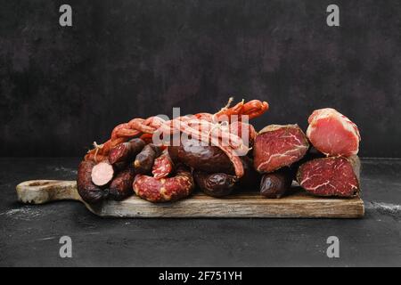 Assortment of pork sand beef ausages, ham and meat on wooden cutting board Stock Photo