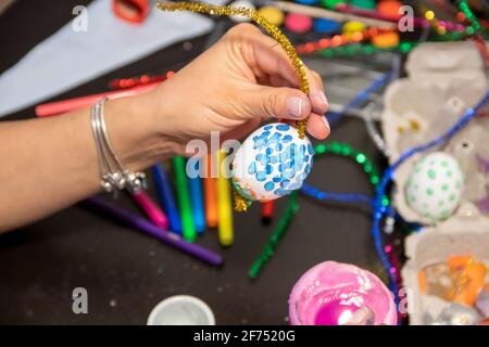 Easter egg painting and decorating activity concept: Human hands holding colorful handmade Easter eggs. Preparation for holidays. Stationary objects Stock Photo