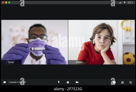 Concentrated young black male doctor in medical uniform and mask showing test tube with blood sample to attentive boy with earbuds patient during vide Stock Photo