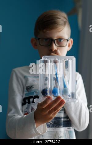 Young boy breaths deep exercise with incentive spirometer. Threeflow respiratory exerciser for help perform normal breathing. Stock Photo
