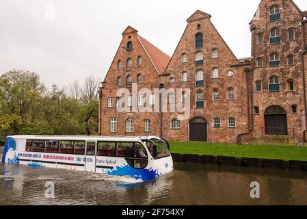 An amphibious sightseein bus passes by the historic warehouses of Lübeck, that were formerly used to store salt. Stock Photo