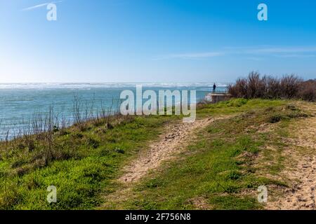 Ars-en-Ré, France - February 24, 2020: Man seen from afar, looking at the sea on top of a blockhaus, on a sunny late winter day Stock Photo