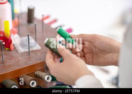 Womans hand holding skeins of green thread Stock Photo