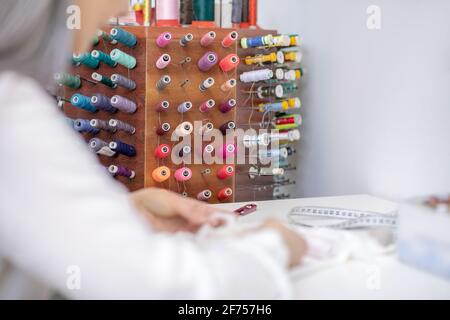Special stand with colored threads and sewing hands Stock Photo